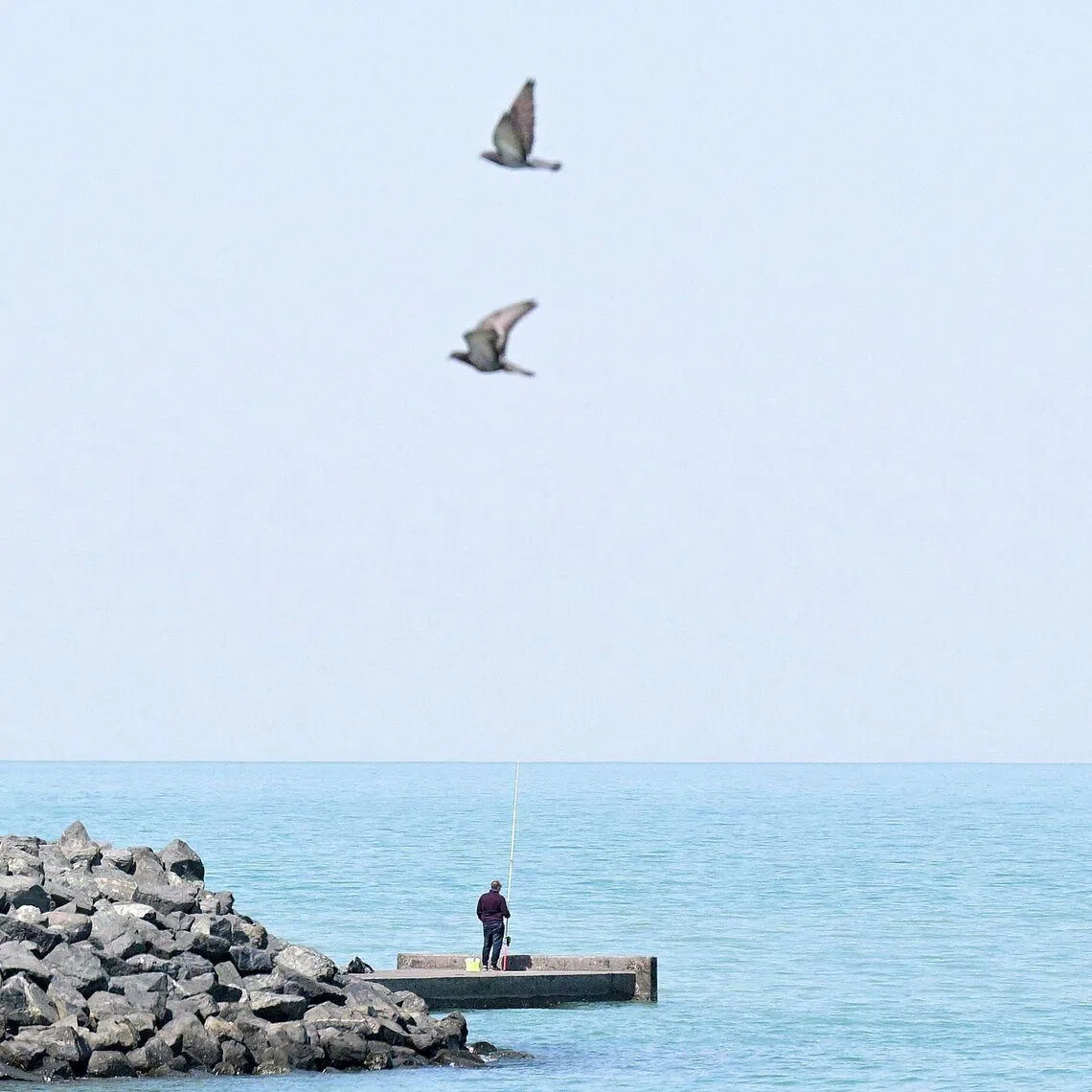 A man fishes in the Gulf waters off Kuwait City on March 10. Drones hit a fuel tank, causing a fire at Kuwait International Airport on March 25. 