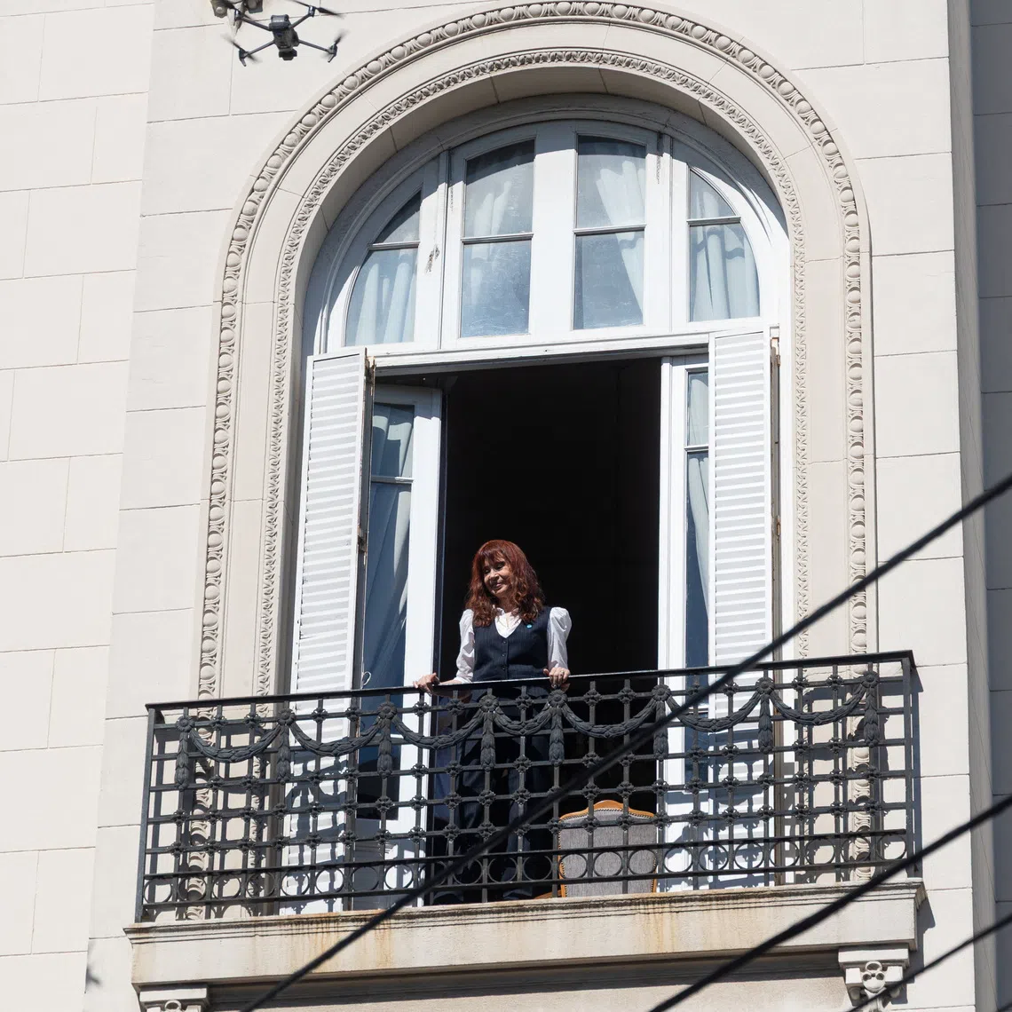 Argentina's former President Cristina Fernandez de Kirchner stands on the balcony of her home, where she is currently staying under house arrest, as her supporters gather outside, on the day of a hearing in the \"Causa Cuadernos\" corruption trial after being summoned to testify, following the rejection of defense motions seeking to nullify the proceedings, in Buenos Aires, Argentina, March 17, 2026. REUTERS/Tomas Cuesta
