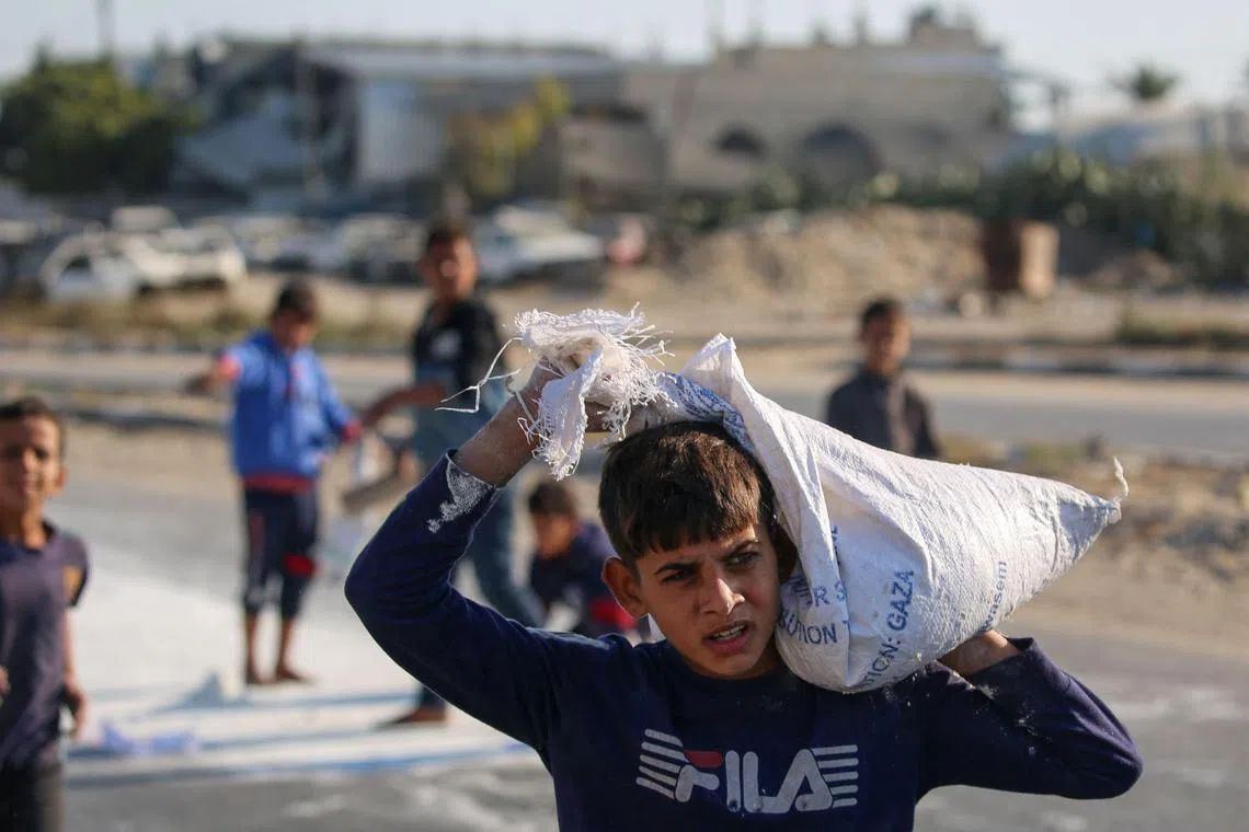 Palestinian boys scraping up flour from the ground after a bag fell from an aid truck in Deir el-Balah, in the central Gaza Strip, on Nov 5.