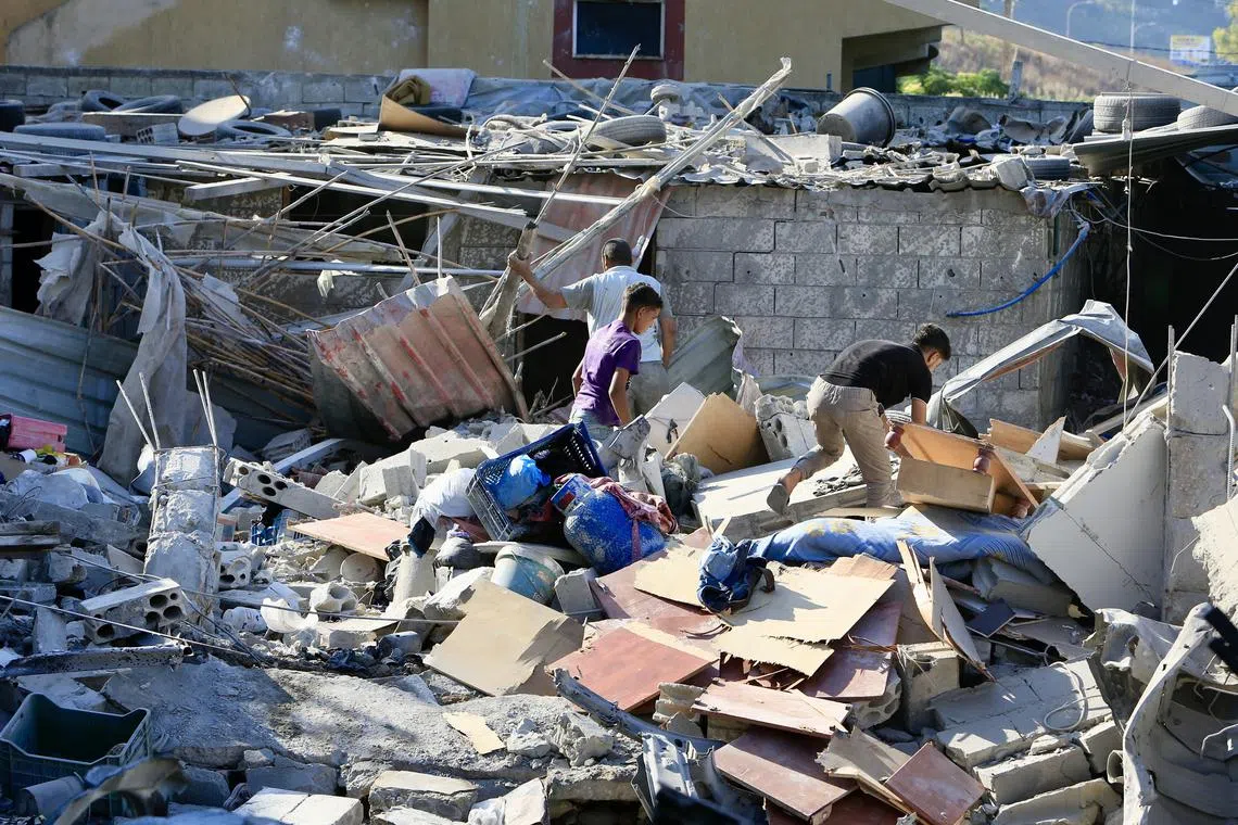 Lebanese people search for their belongings in a damaged building after Israeli strikes on South Lebanon, on Sept 23, 2024.
