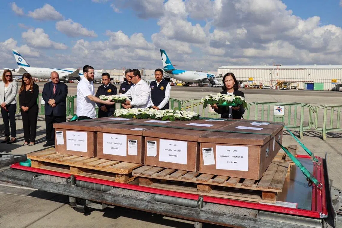 Thailand's Ambassador to Israel Pannabha Chandraramya (R) laying wreaths on the coffins of Thai workers killed in Israel, at Ben-Gurion Airport, Tel Aviv, on Oct 19.