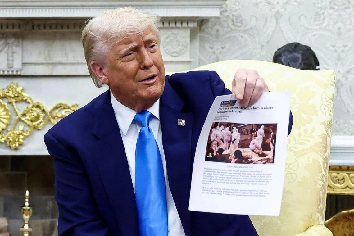 U.S. President Donald Trump shows a copy of an article that he said its about white South Africans who had been killed, in the Oval Office of the White House in Washington, D.C., U.S., May 21, 2025. REUTERS/Kevin Lamarque