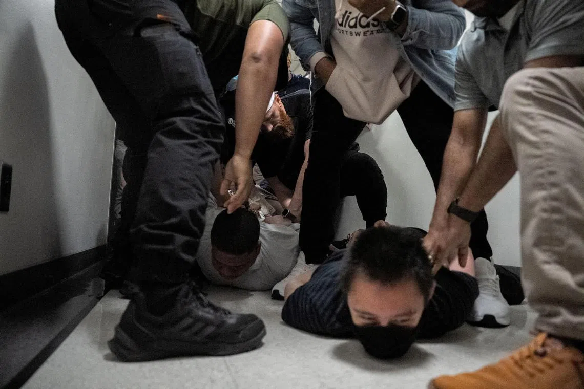 A migrant and a legal observer lay on the floor as they are detained by federal immigration officers at US immigration court in Manhattan, New York.