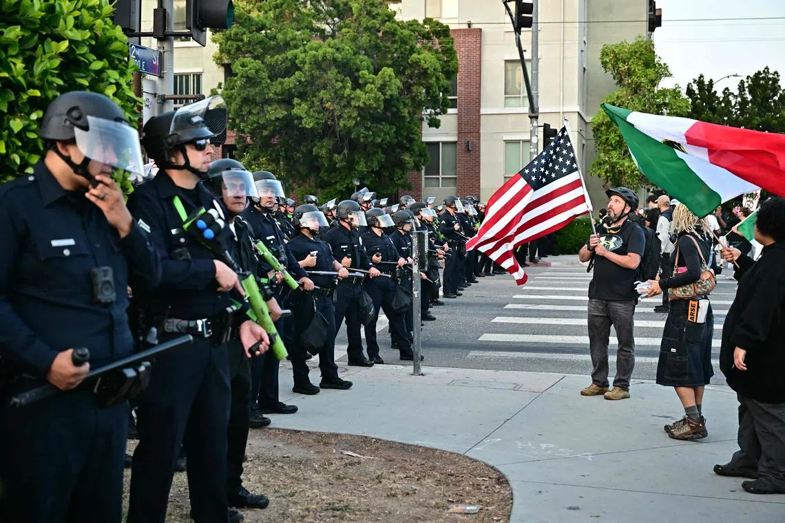 Protestes waving Mexican and US flags face off with police during a protest in downtown Los Angeles, on June 9.