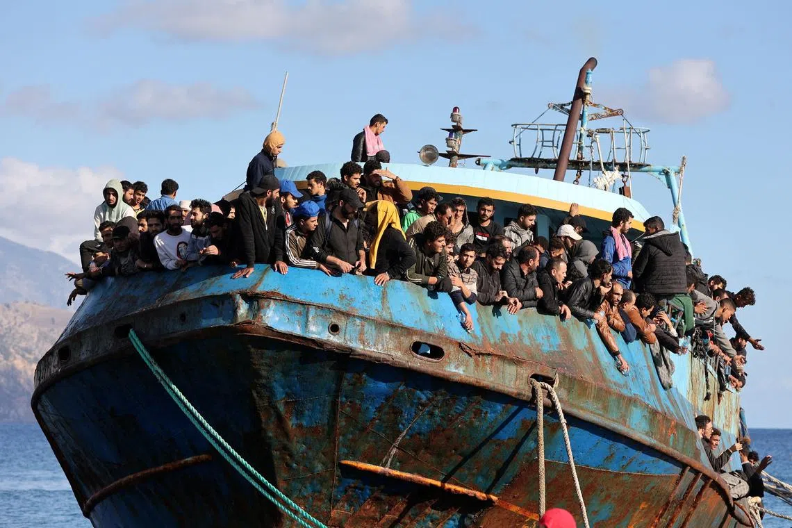 FILE PHOTO: Migrants sit onboard a fishing boat at the port of Paleochora, following a rescue operation off the island of Crete, Greece, November 22, 2022. REUTERS/Stringer/File Photo