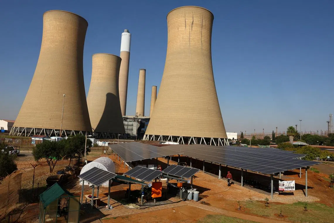 FILE PHOTO: Solar panels are seen near the cooling towers of a retired coal-fired Komati Power Station, operated by Eskom, near Komati village, in the Mpumalanga province in South Africa, May 9, 2024. REUTERS/Siphiwe Sibeko/File Photo