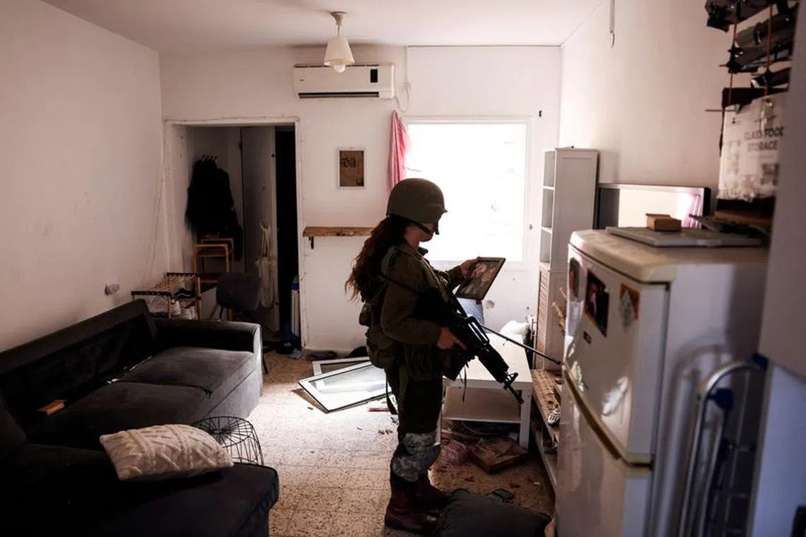 An Israeli soldier looks at a family photograph in an abandoned home, following a deadly infiltration by Hamas gunmen from the Gaza Strip, in Kibbutz Kfar Aza in southern Israel, October 15, 2023. REUTERS/Ronen Zvulun