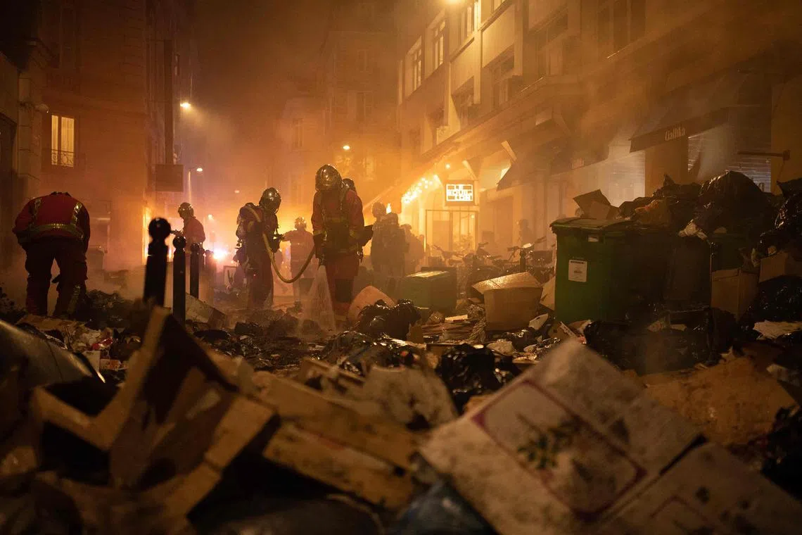 Firefighters extinguishing a fire during a demonstration, after the French government pushed a pensions reform through parliament, in Paris on March 23, 2023. 