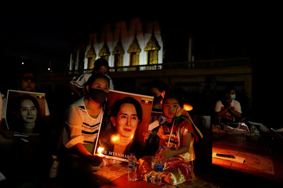 Migrants protesting against the military junta in Myanmar hold a picture of leader Aung San Suu Kyi, during a candlelight vigil at a Buddhist temple in Bangkok, Thailand, March 28, 2021. REUTERS/Jorge Silva
