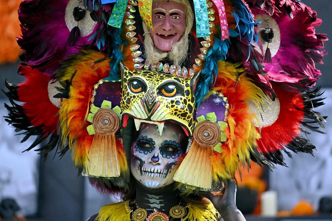TOPSHOT - A woman dressed as a traditional Catrina stands in front of an altar displaying photographs of deceased Formula One drivers during a welcome ceremony for the drivers at the Hermanos Rodriguez racetrack in Mexico City on October 29, 2026, ahead of the Mexico City Formula One Grand Prix. (Photo by YURI CORTEZ / AFP)