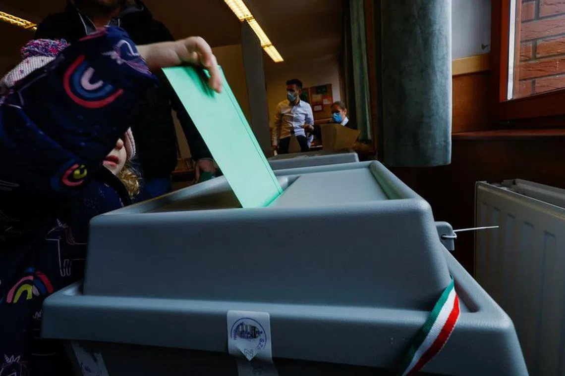 A child casts a ballot on behalf of a voter at a polling station during Hungarian parliamentary elections in Veresegyhaz, Hungary April 3, 2022. REUTERS/Leonhard Foeger/File Photo