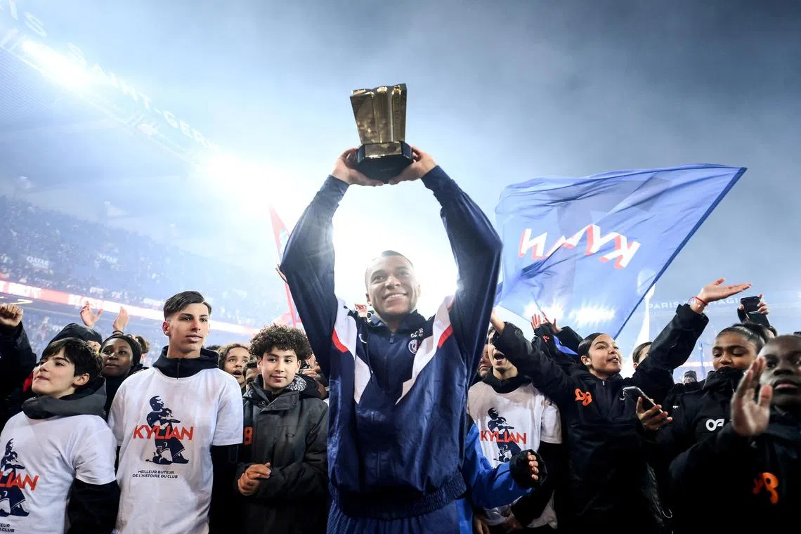 Paris St-Germain's Kylian Mbappe hoisting the trophy to mark his record 201 club goals.