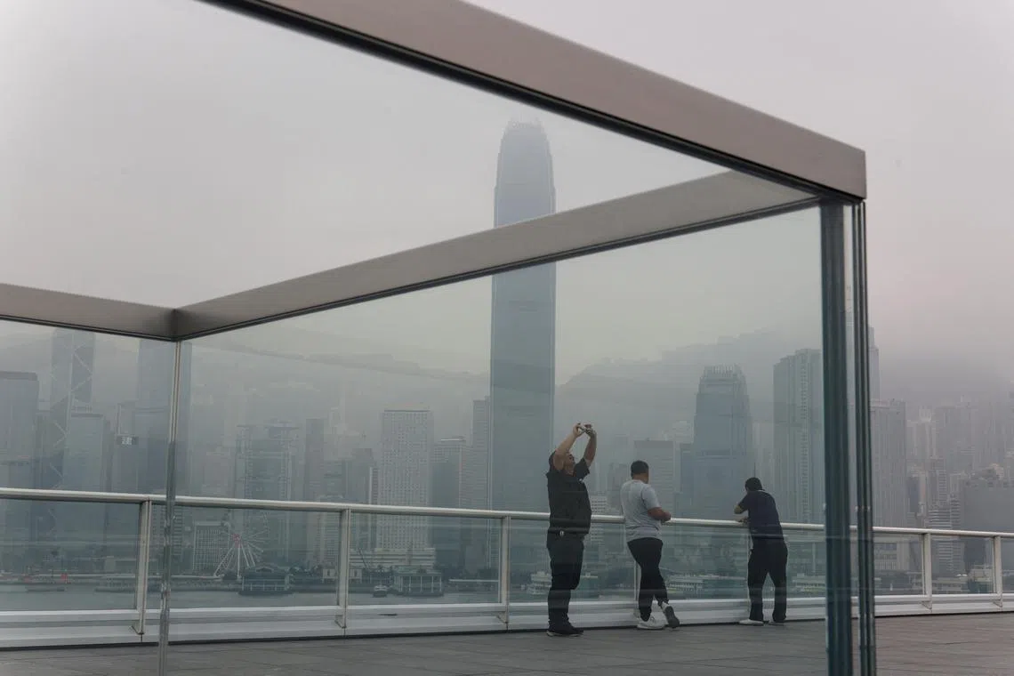 FILE PHOTO: People take photos at the waterfront during a foggy day in Hong Kong, China, March 6, 2024. REUTERS/Tyrone Siu/File Photo