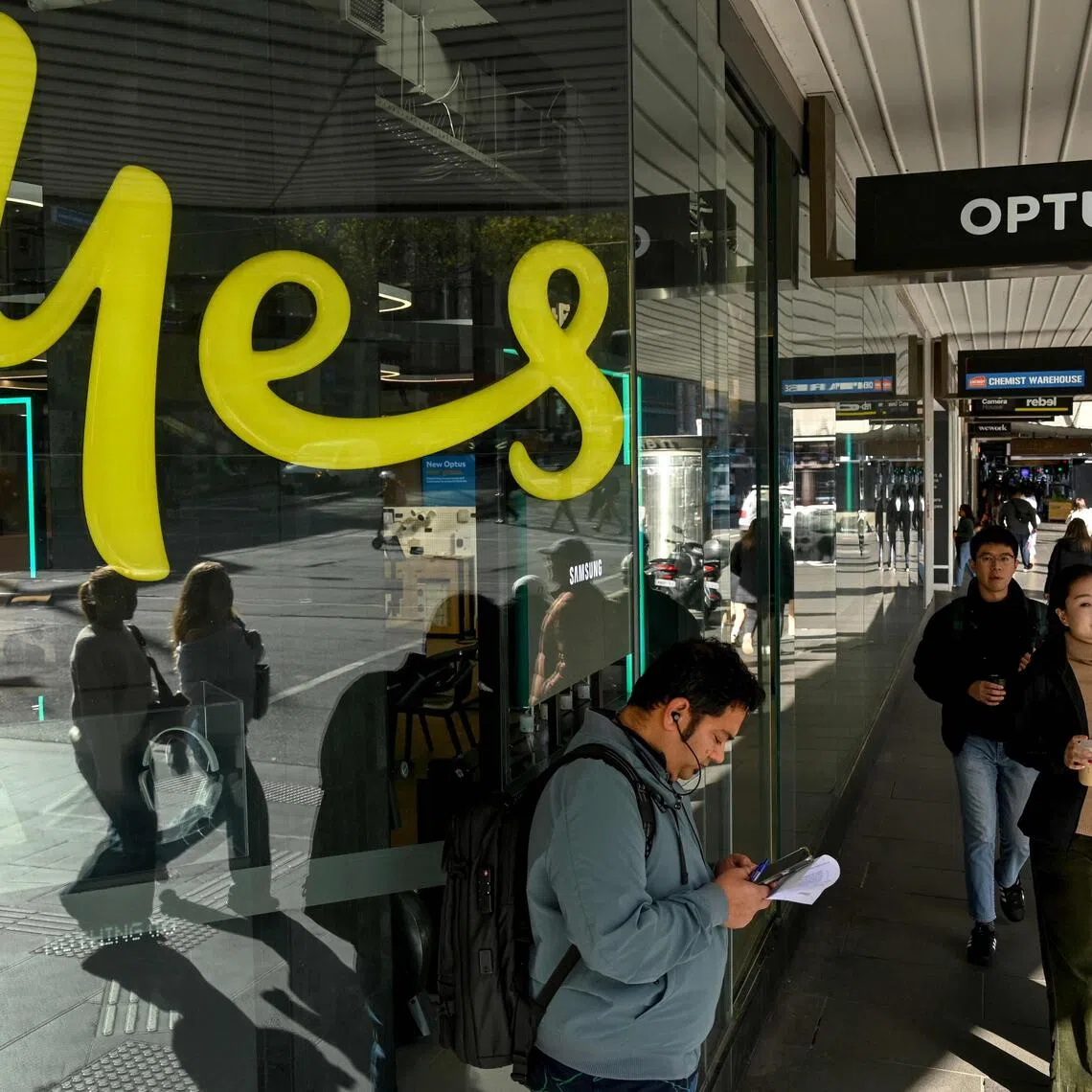 People pass by an Australian communications company Optus store in Melbourne on September 22, 2025. The Australian government said September 20 that telco firm Optus "let Australians down" after three people died during a network outage that prevented calls to emergency services. (Photo by William WEST / AFP)