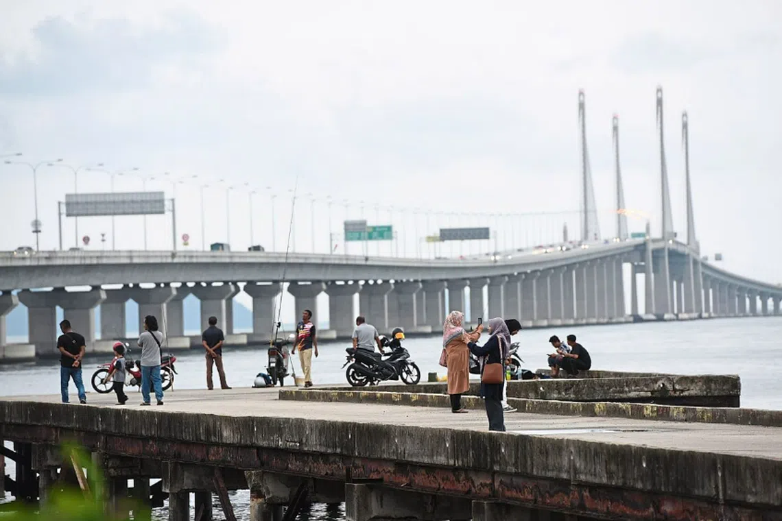 People gathering on a pier set to be used by water taxis, close to the second Penang Bridge in Batu Maung, Penang. 