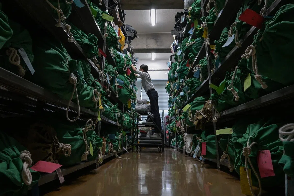 This photo taken on August 2, 2024 shows an employee working on thousands of items - all bagged, tagged and organised based on where and when they were lost - at the Tokyo Metropolitan Police Department Lost and Found Centre in the Iidabashi area of central Tokyo. Soft toys, forlorn suitcases and a forest of umbrellas: welcome to Tokyo's vast police lost-and-found centre, where everything is meticulously tagged and sorted to hasten a return to its rightful owner. (Photo by Richard A. Brooks / AFP) / TO GO WITH: Tokyo-lifestyle-transport, REPORTAGE by Natsuko FUKUE