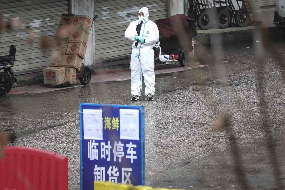 A 2020 photo shows a health worker in protective clothing collecting samples at a market in China's Wuhan.
