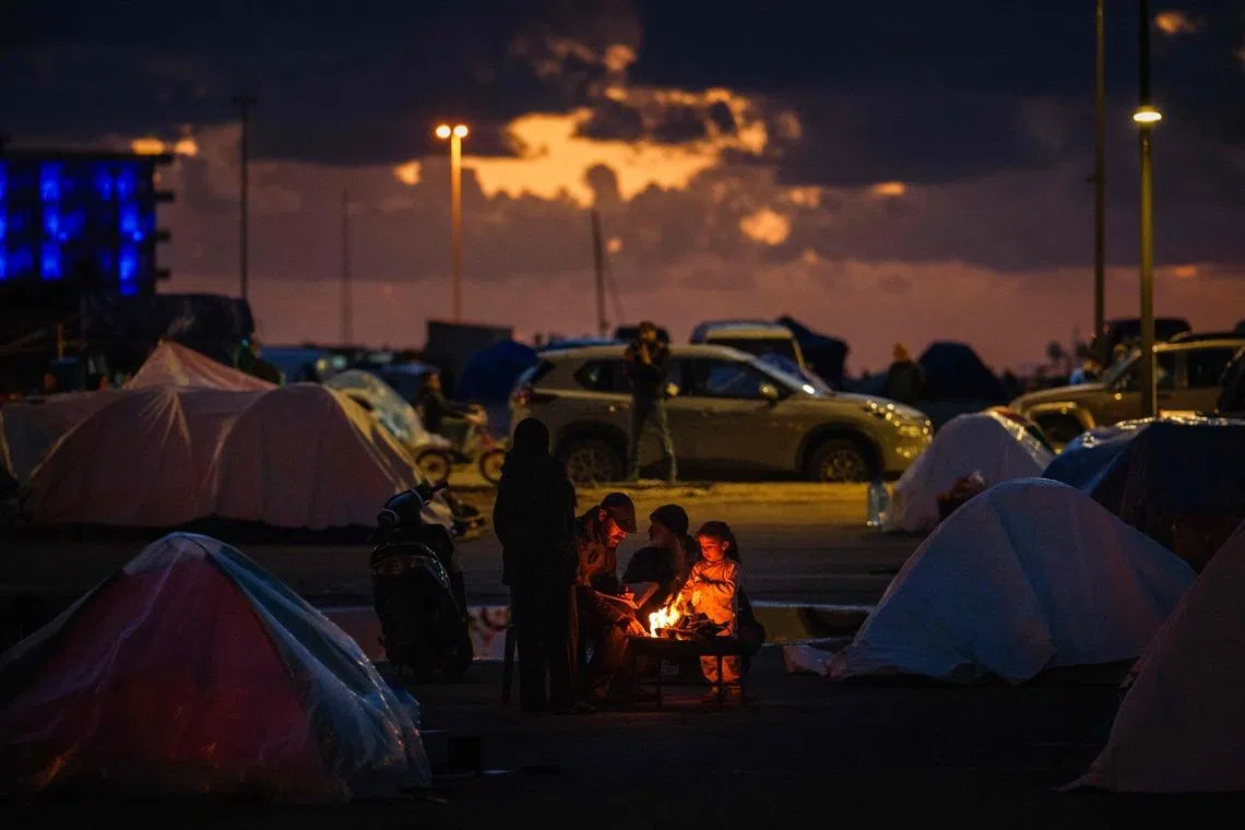 Displaced people warming up around a fire outside their tent along Beirut's seafront area on March 30, 2026. Israel renewed its bombardment of Beirut's southern suburbs while continuing air strikes on Lebanon's south.