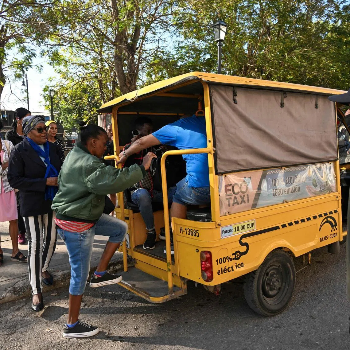 People line up to board an electric tricycle on a street in Havana, on Feb 13.
