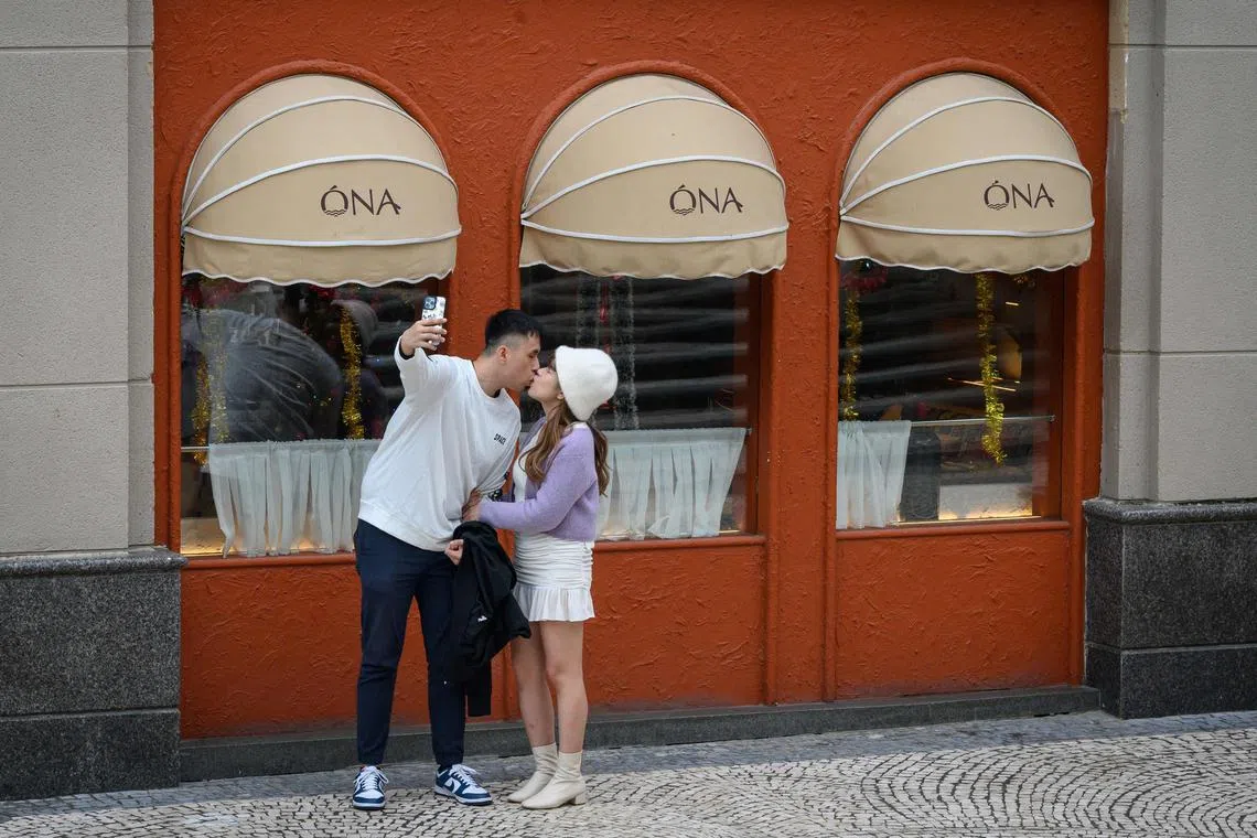 Um casal se beija para uma selfie em frente a um restaurante no Discovery Bay, na ilha de Lantau, em Hong Kong, em 26 de dezembro de 2024. (Foto de Mladen ANTONOV / AFP)