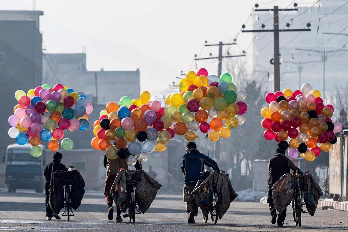 TOPSHOT - Afghan balloon vendors walk with their bicycles to look for customers, near a market in Kabul on January 8, 2025. (Photo by Wakil KOHSAR / AFP)