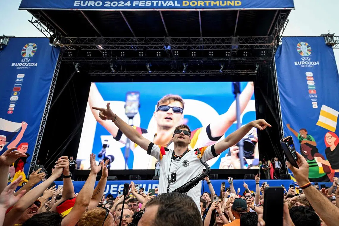 German saxophonist Andre Schnura performing for Germany supporters at the fan zone and public viewing area of the Westfalenpark in Dortmund on June 29, ahead of the hosts' last-16 clash with Denmark.