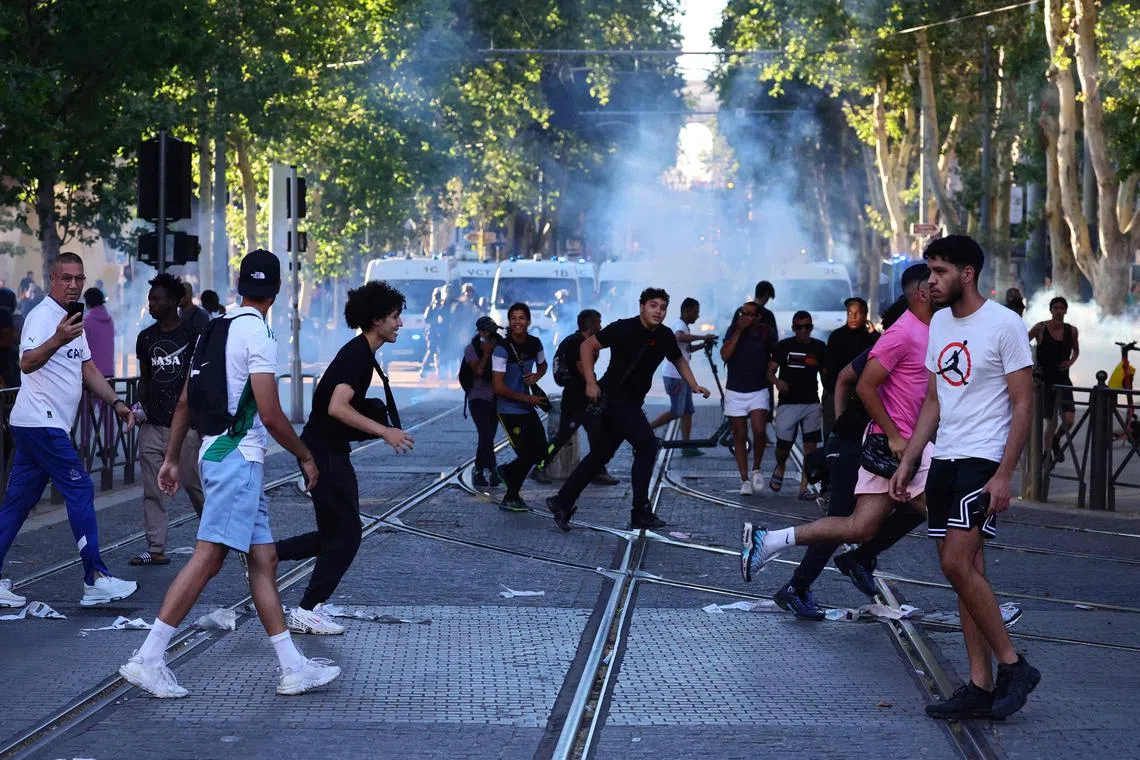 Protesters run from launched tear gas canisters, during clashes with police in Marseille.