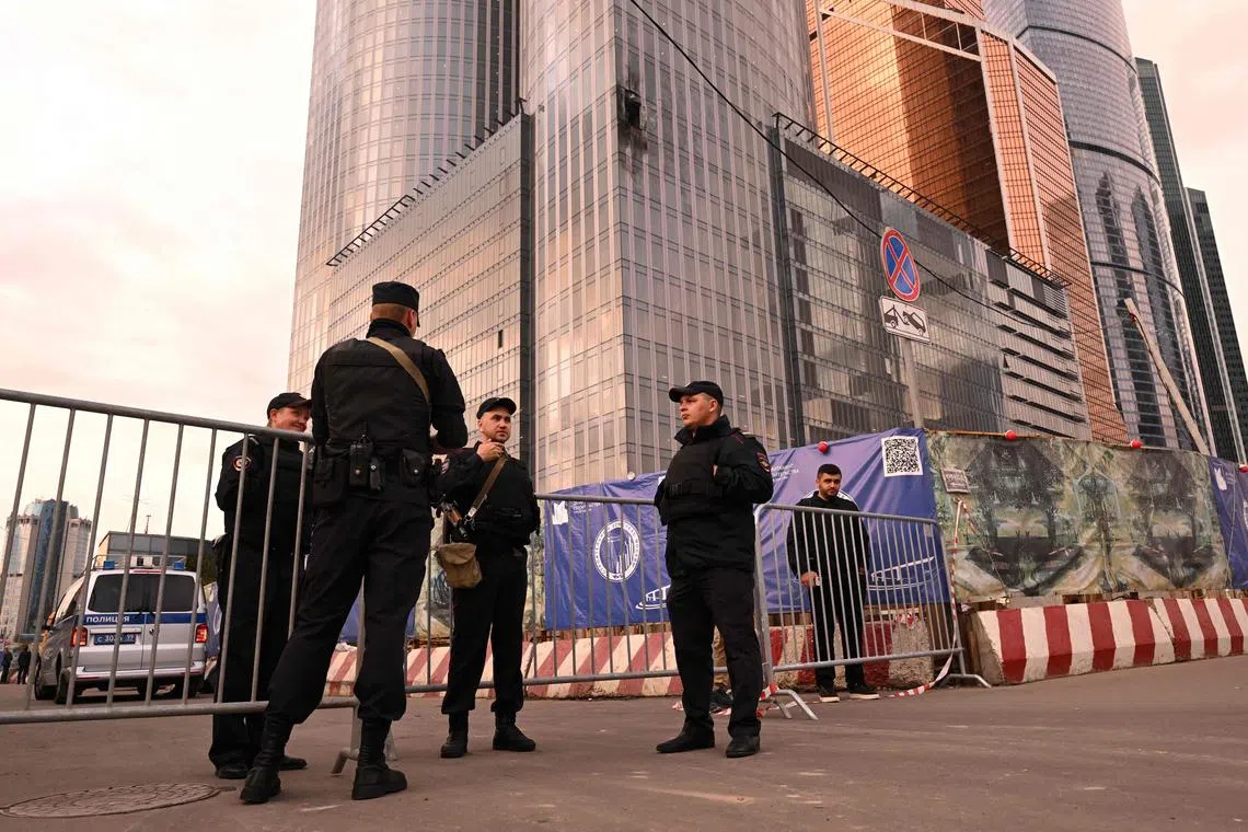 Officers stand next to a damaged building of the Moscow International Business Center following a drone attack in Moscow on Aug 23.