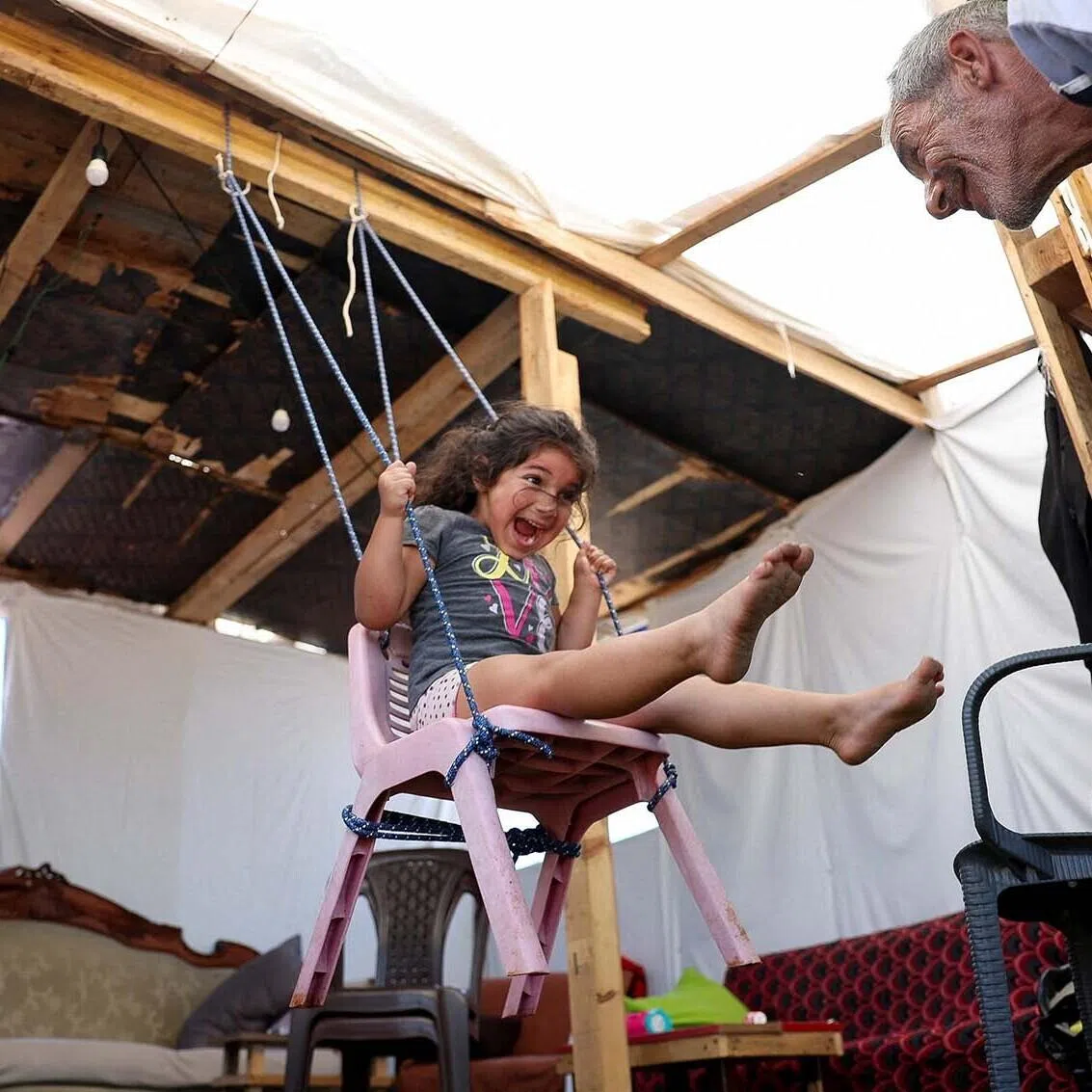 A girl and her grandfather playing inside a tent used as a shelter at Beirut waterfront, Lebanon, June 4.
