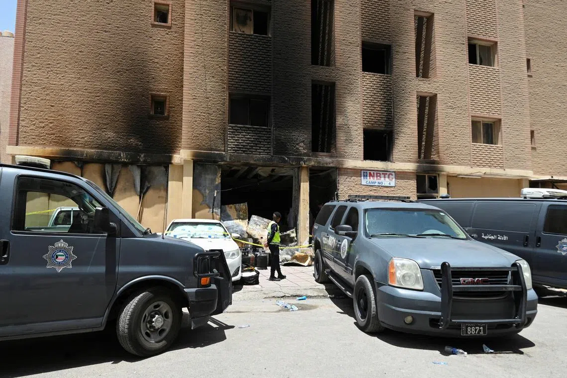A Kuwaiti police officer is seen in front of a burnt building following a deadly fire, in Mangaf, southern Kuwait, June 12, 2024. REUTERS/Stringer