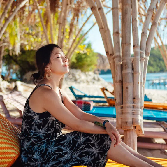 Asian woman sitting on a chair by the beach