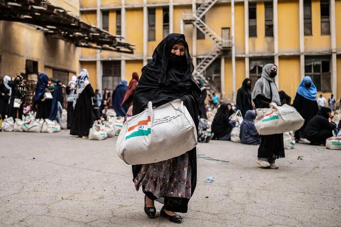 Afghan women receive food aid donated by the Indian government, in Kabul on May 18, 2025. (Photo by Wakil KOHSAR / AFP)
