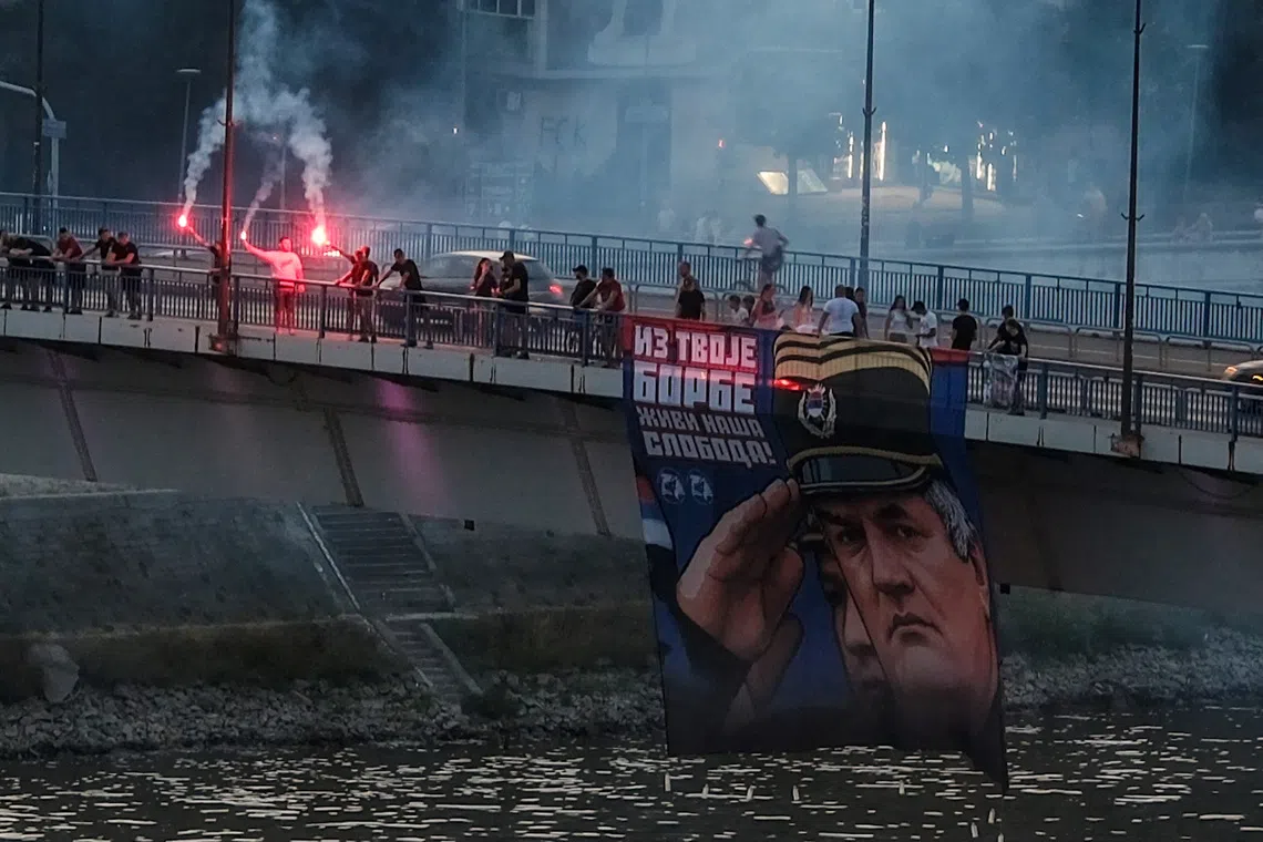 Supporters of the deceased Bosnian Serb general Ratko Mladic hold his picture and light flares on the Varadinski Bridge In Novi Sad Serbia, Serbia, August 27, 2026. REUTERS/Stefan Stojanovic