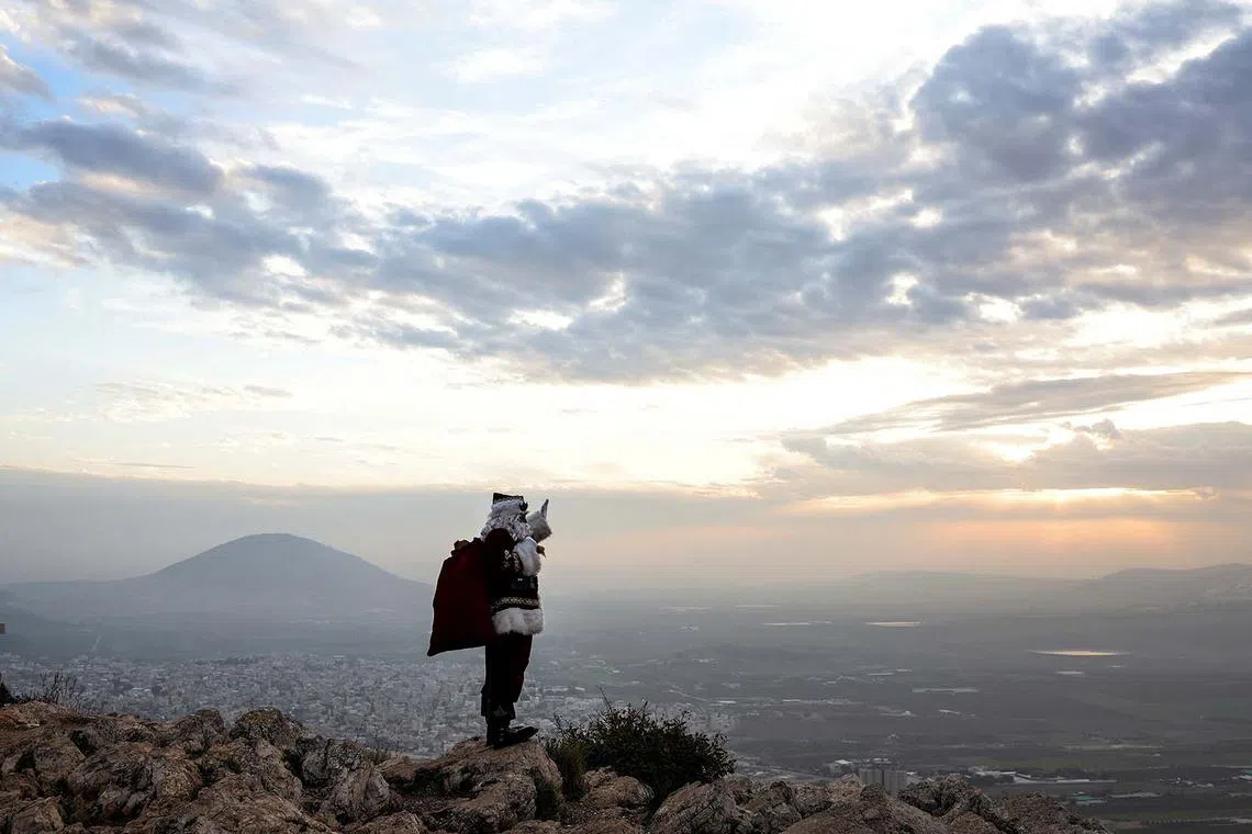 Issa Kassissieh, dressed as Santa Claus, waves and poses for members of the media as he stands on Mount Precipice in front of Mount Tabor close to Nazareth in northern Israel, December 12, 2022. REUTERS/Nir Elias TPX IMAGES OF THE DAY