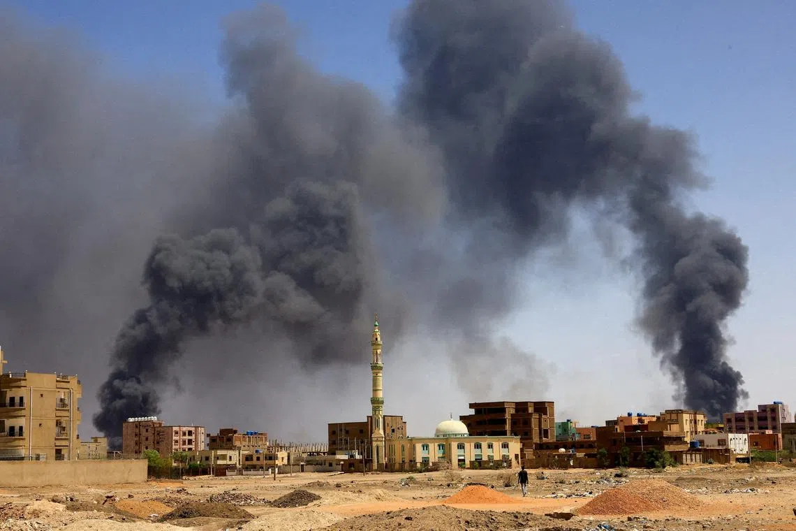 FILE PHOTO: A man walks while smoke rises above buildings after aerial bombardment, during clashes between the paramilitary Rapid Support Forces and the army in Khartoum North, Sudan, May 1, 2023. REUTERS/Mohamed Nureldin Abdallah/File Photo