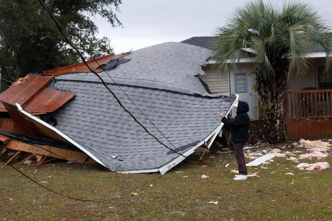 A resident checks a collapsed roof after a line of storms roared through the area of Perdido Key near Pensacola, Florida, on Jan 9.