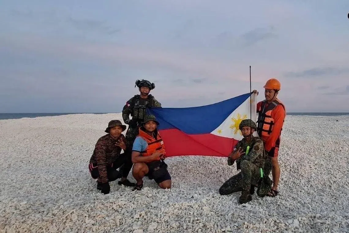 Philippine coast guard personnel holding a Philippine flag during an inter-agency maritime operation on Sandy Cay.