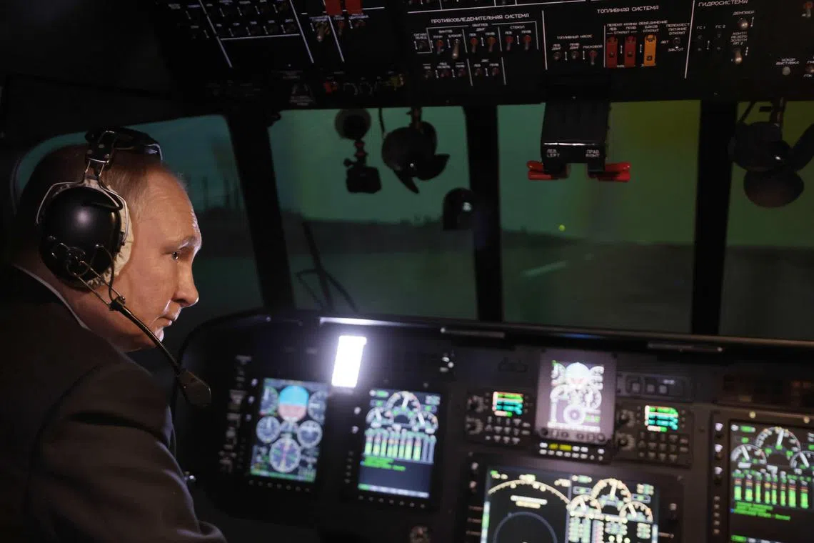 Russian President Vladimir Putin sits in a flight simulator during a visit to a Russian helicopter maker, on March 14, 2023.