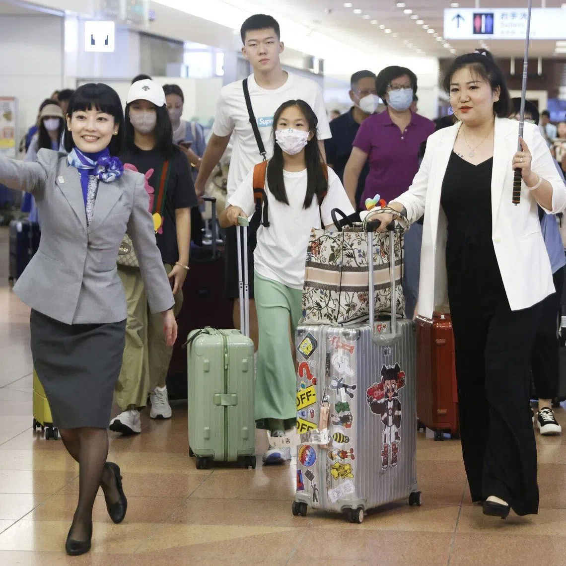 An All Nippon Airways Co. (ANA) employee, left, escorts a group of Chinese tourists and a tour conductor, right, at the arrival lobby of Haneda Airport in Tokyo, Japan, on Wednesday, Aug. 23, 2023. China lifted a ban on group tours this month to a slew of countries including the US, UK, Australia, South Korea and Japan, in a major test of demand for overseas travel from what was once the world’s biggest source of tourists. Photographer: Kiyoshi Ota/Bloomberg