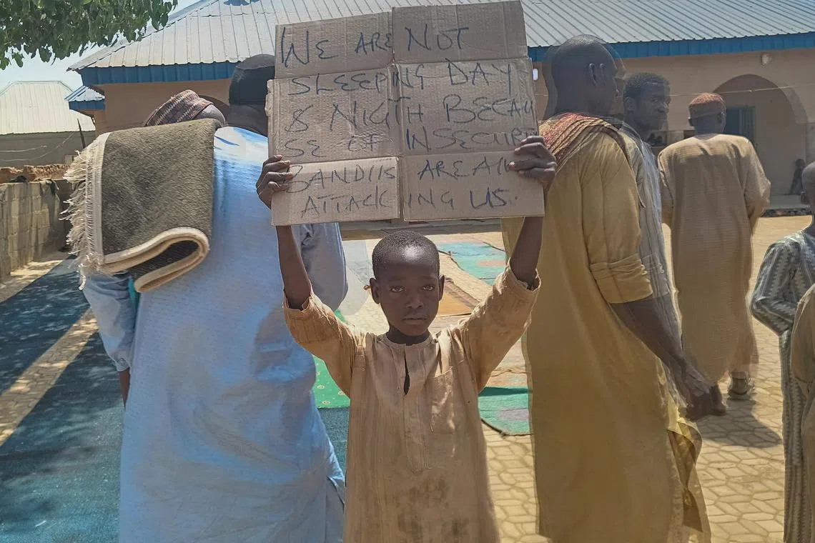 A boy holds a sign to protest against, what a teacher, local councilor and parents said, the kidnapping of hundreds school pupils by gunmen after the Friday prayer in Kaduna, Nigeria March 8, 2024. REUTERS/Stringer/File Photo