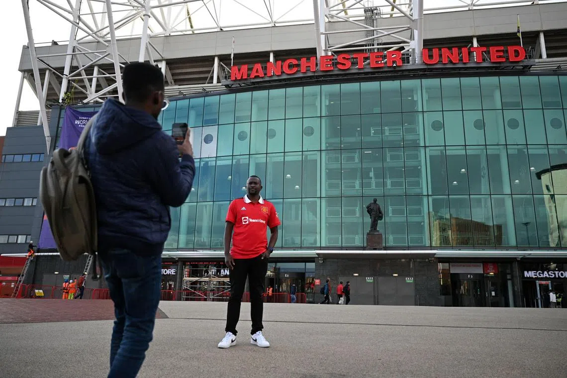A fan poses for a photo outside Manchester United's home ground, Old Trafford.