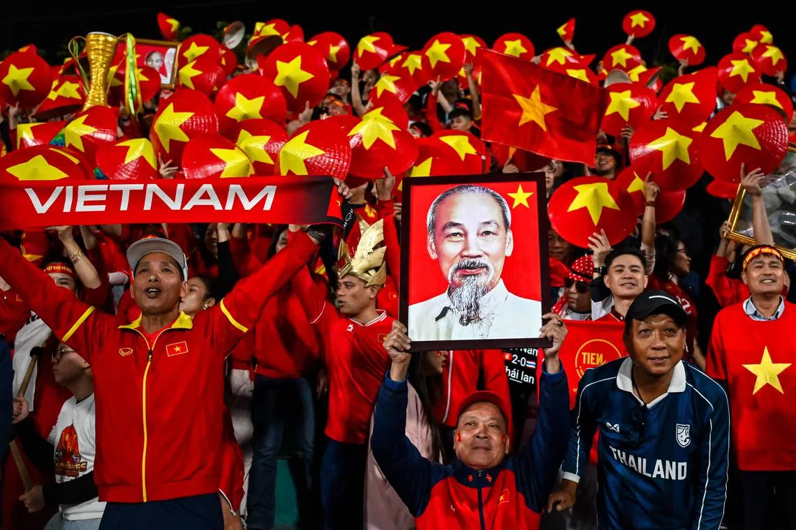 Vietnamnese football supporters holding a portrait of Ho Chi Minh before the start of the 2024 ASEAN Electric Cup final first leg football match between Vietnam and Thailand at the Viet Tri Stadium in Phu Tho province in Vietnam on Jan 2, 2025. 