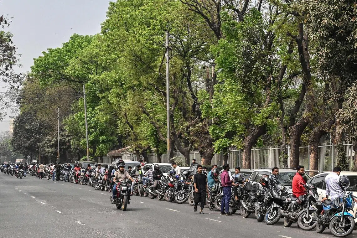 People wait in a queue to refuel their vehicles near a fuel station in Dhaka on March 8, 2026.  