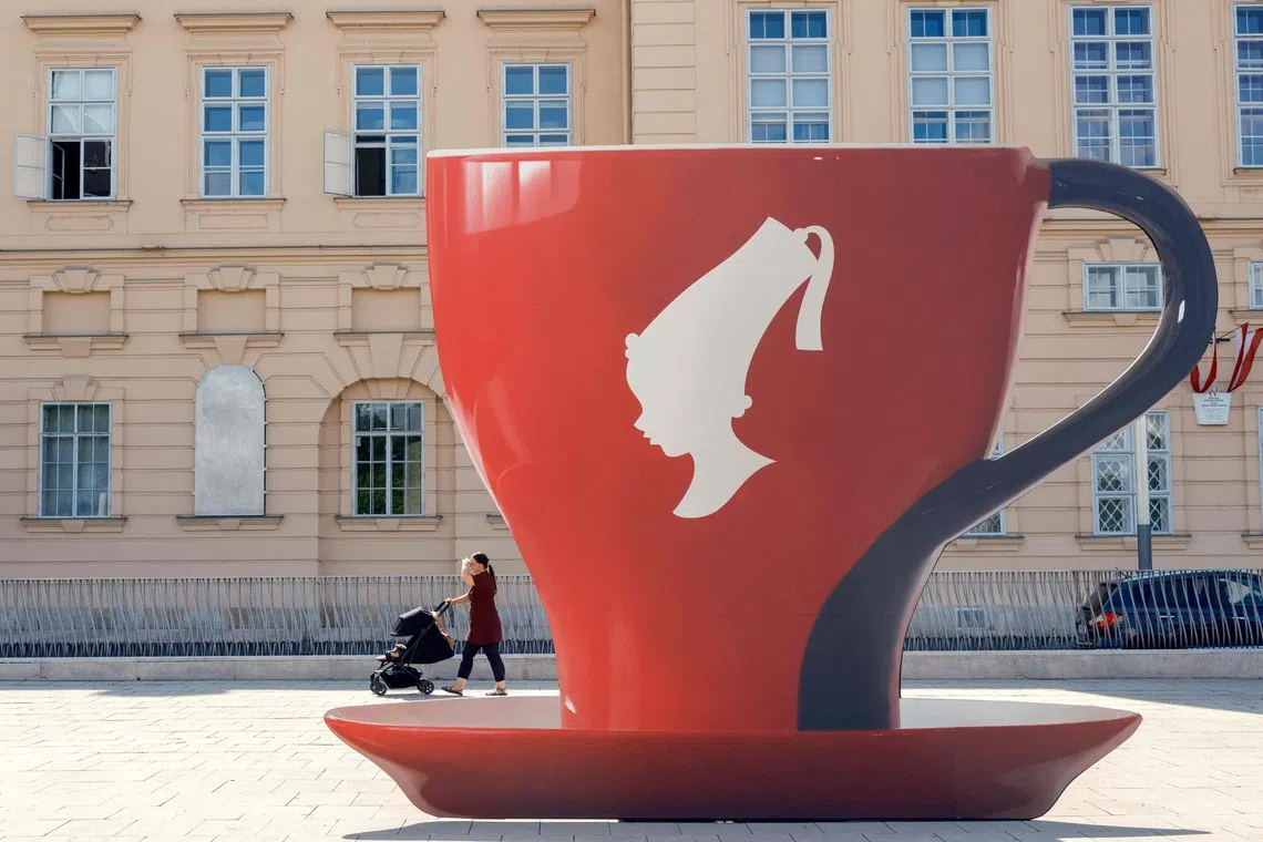 TOPSHOT - A woman pushes a stroller past an oversized coffee cup to promote Saturday’s barista event at Museum Quartier on a sunny day in Vienna, Austria, on September 2, 2026. (Photo by Joe Klamar / AFP)