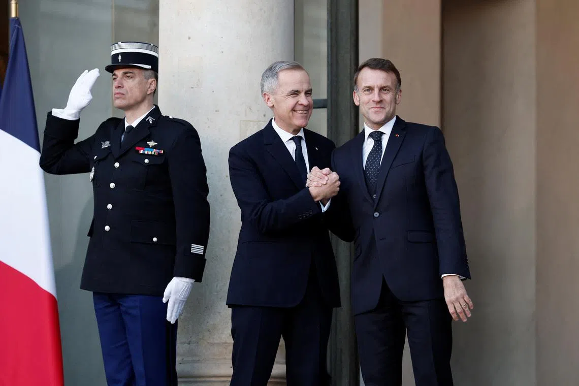 French President Emmanuel Macron (right) welcomes Canada's Prime Minister Mark Carney as he arrives for a summit at the Elysee Palace in Paris, France, on Jan 6.