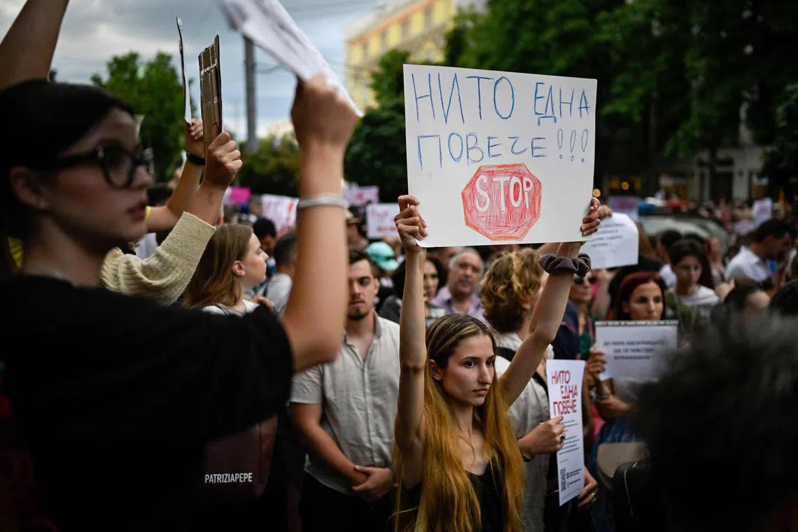 A woman holds a placard reading ""Not a single one more!!! Stop" during a demonstration against domestic violence.