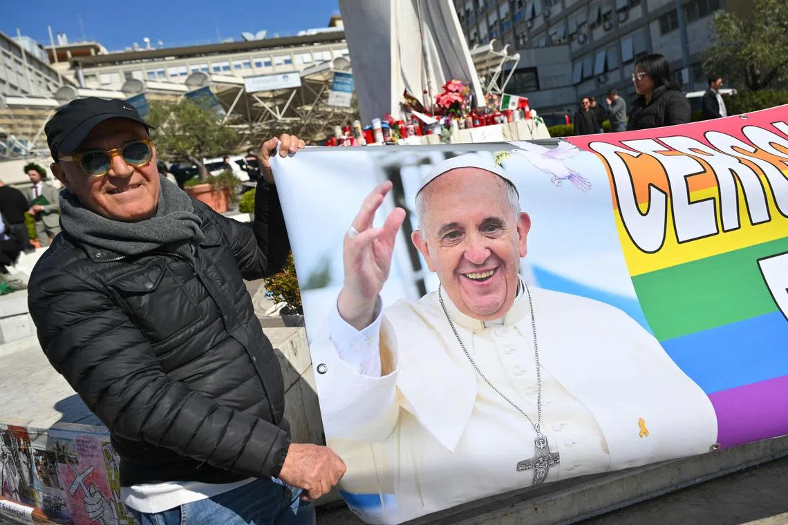 People holding a banner featuring an image of Pope Francis outside the hospital where he is being treated for pneumonia, in Rome, on March 6.