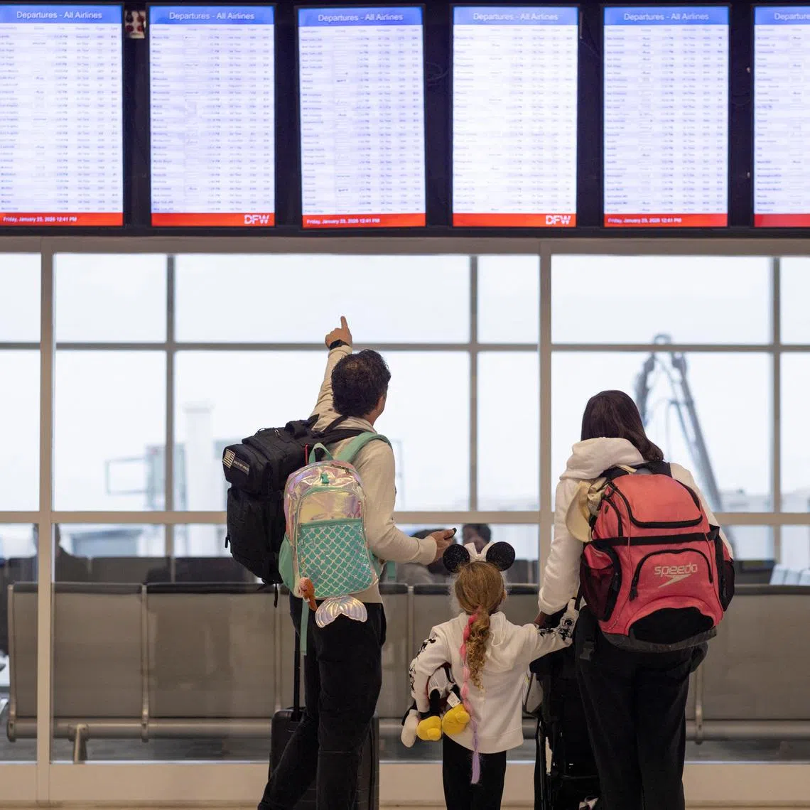 People check the flight tracker screens at the Dallas Fort Worth International Airport in Fort Worth, Texas, U.S., January 23, 2026.  REUTERS/Alyssa Pointer