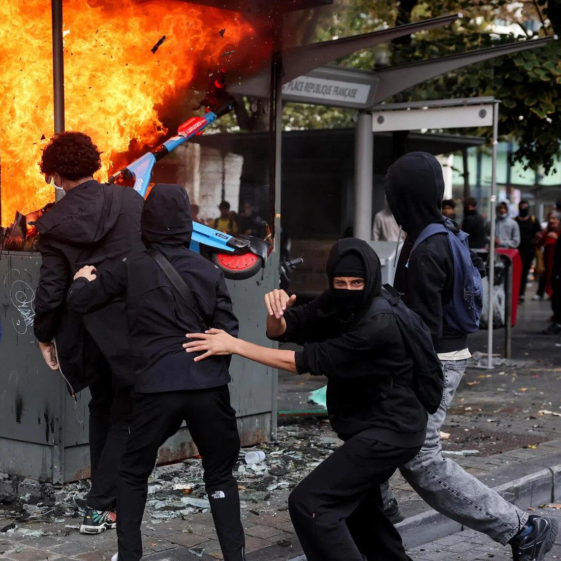 Protesters in Liege on Oct 7, attempting to put an electric scooter into a burning structure. Hundreds of students took to the streets, with Belgian media reporting 107 arrests relating to property damage and arson.