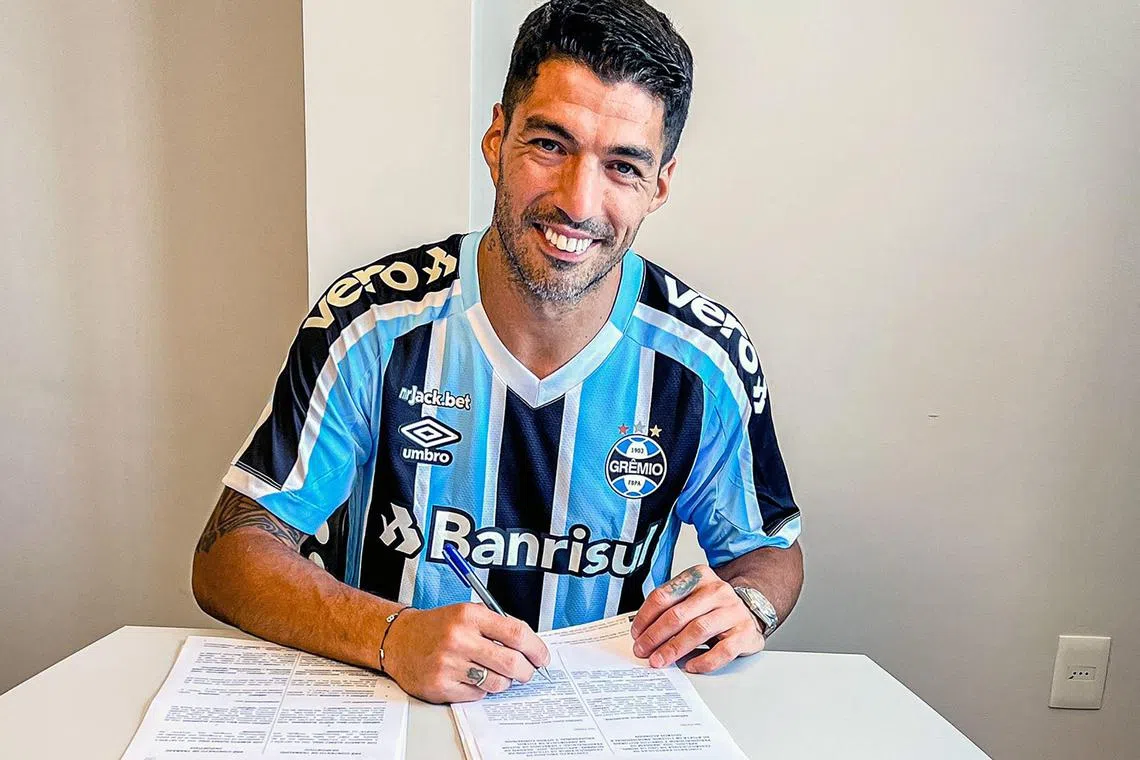 Handout picture released by Divulgacao Gremio FBPA on December 31, 2022, showing Uruguayan international striker Luis Suarez posing as he signs a two-year contract with Brazilian football club Gremio, at his Complejo Suarez sports complex in Ciudad de la Costa, Canelones, Uruguay. - Suarez has signed a two-year deal with Gremio, the Porto Alegre side announced on December 31, 2023. The 35-year-old had returned to his boyhood club Nacional last summer, scoring eight goals in 14 matches to help them win the Uruguayan league title. (Photo by DIVULGACAO GREMIO FBPA / AFP) / RESTRICTED TO EDITORIAL USE - MANDATORY CREDIT "AFP PHOTO / DIVULGACAO GREMIO FBPA" - NO MARKETING NO ADVERTISING CAMPAIGNS - DISTRIBUTED AS A SERVICE TO CLIENTS